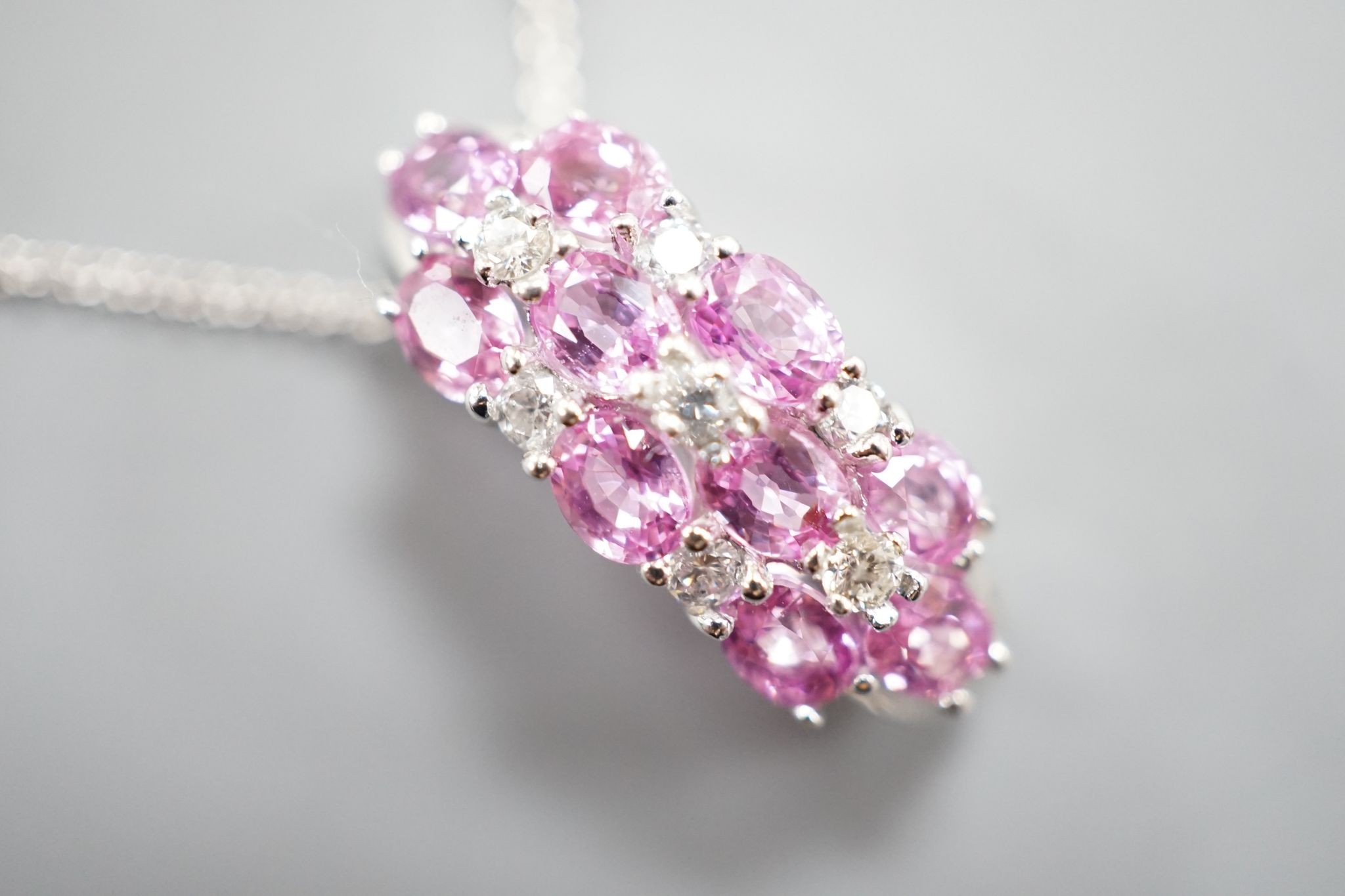 A modern 14k white metal pink sapphire and diamond cluster set pendant, on a 14k fine link chain(knotted)